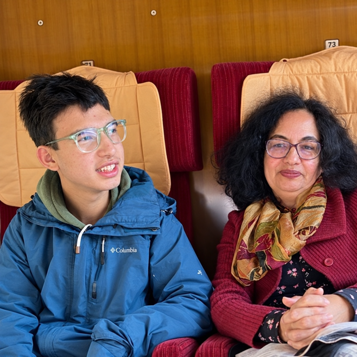 Ein Foto von Yunis und Nadia. Die beiden sitzen in einem Zug.